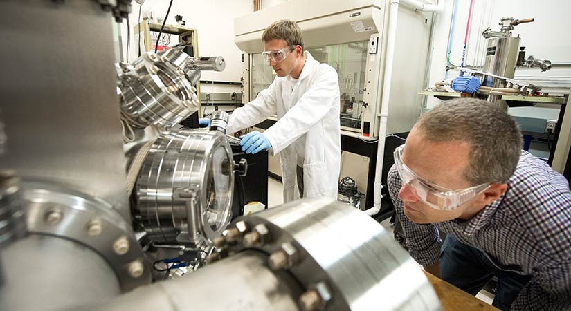 amo-31131 Two researchers wearing protective gear work in a lab setting.